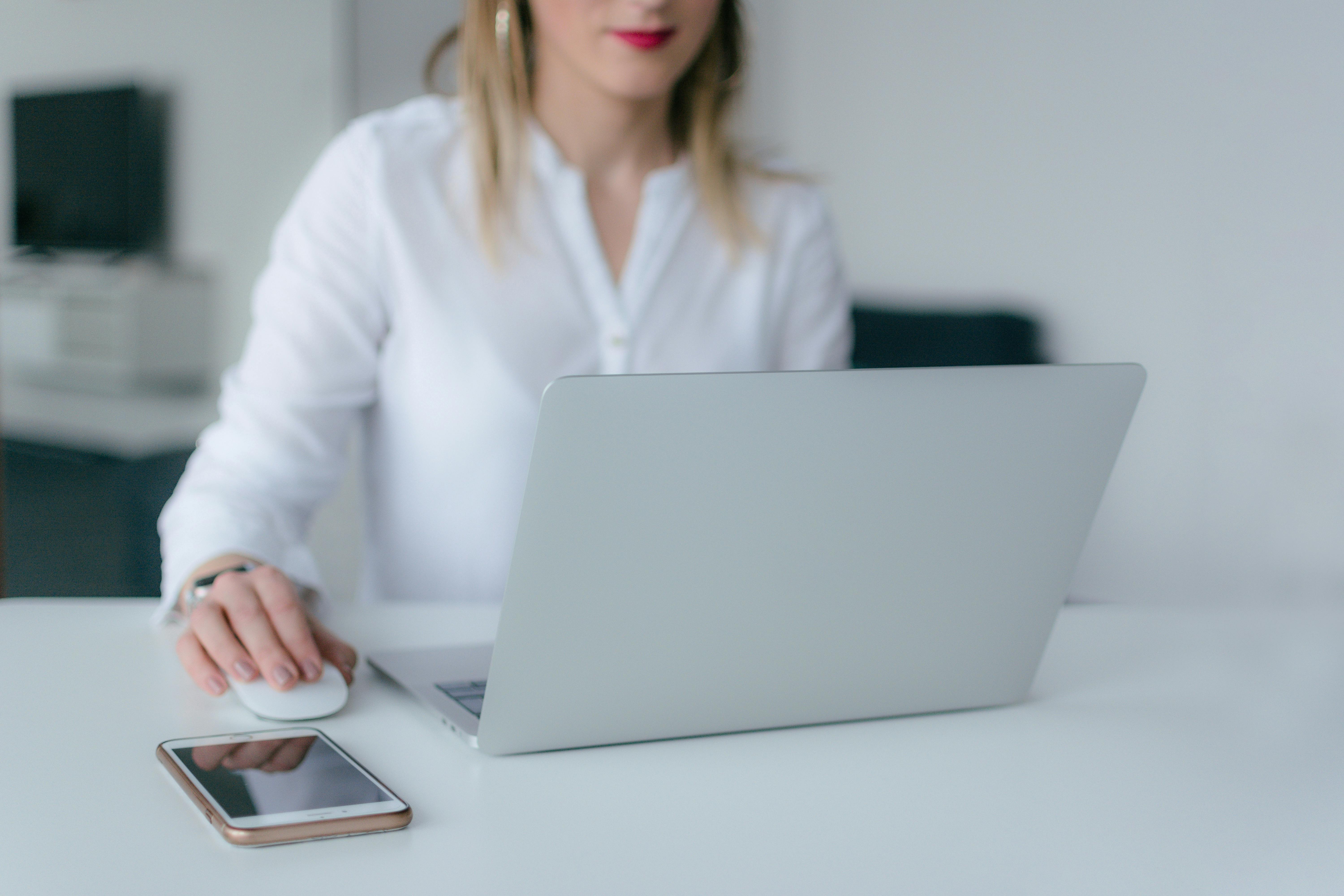 Businesswoman working on her laptop in a bright, modern office with minimalistic decor and natural light