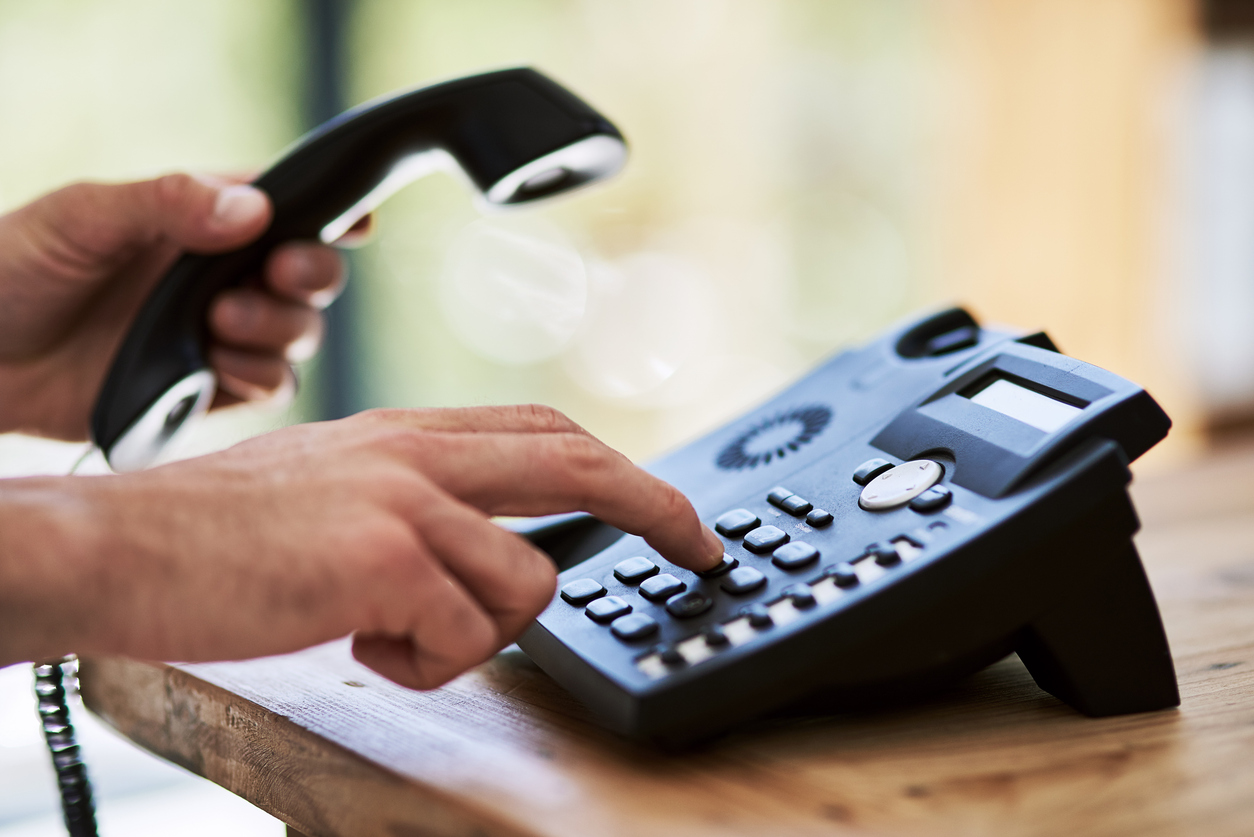 A person is dialing a landline phone.