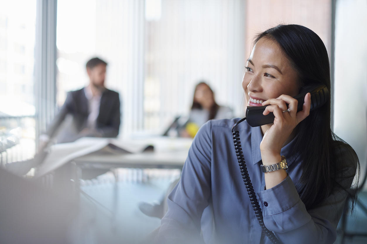 An office team member engaged in a phone call, efficiently managing business communications amidst a professional workspace.