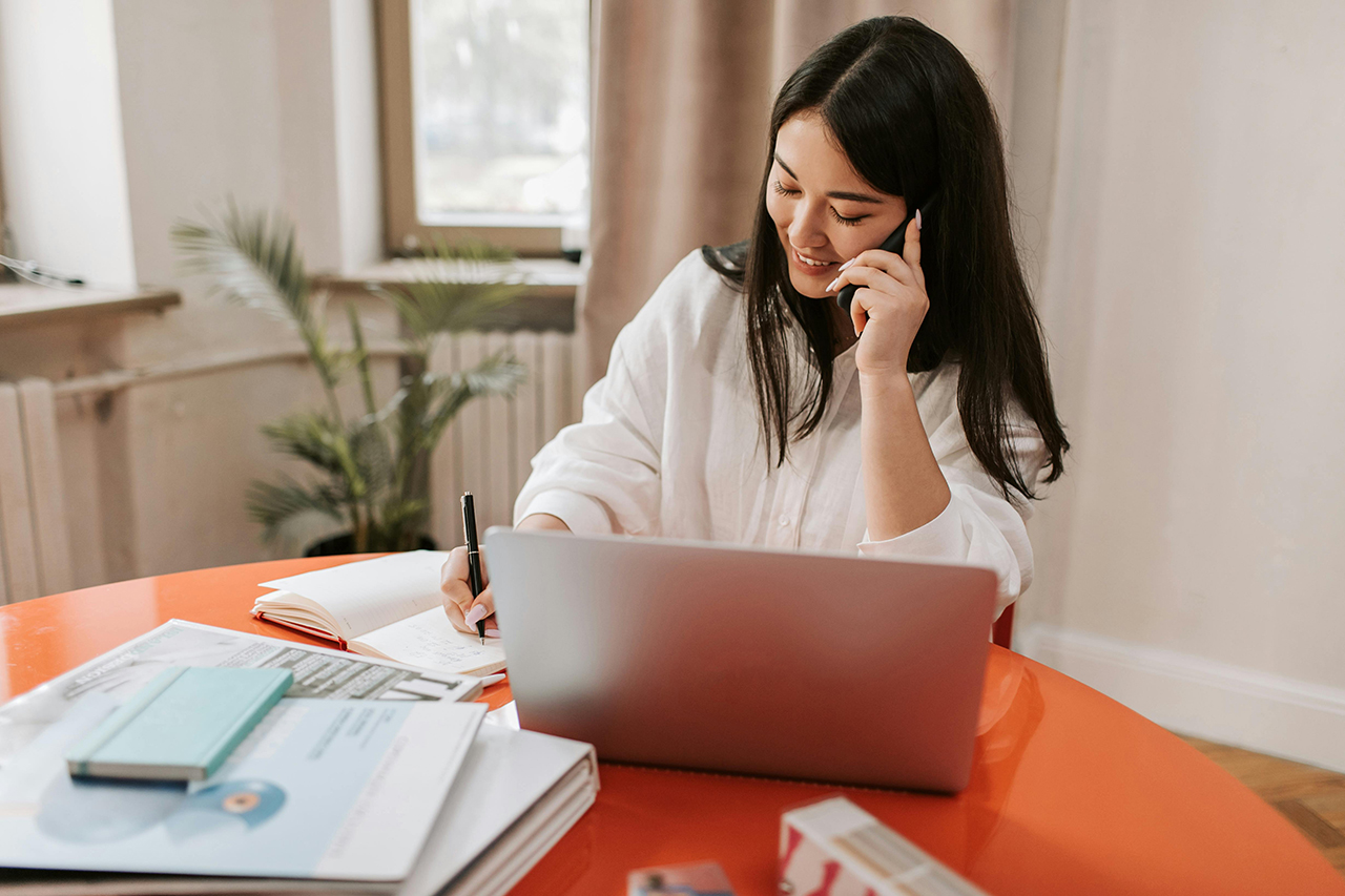 A woman in an office, confidently communicating on the phone, with a focused and professional demeanor.